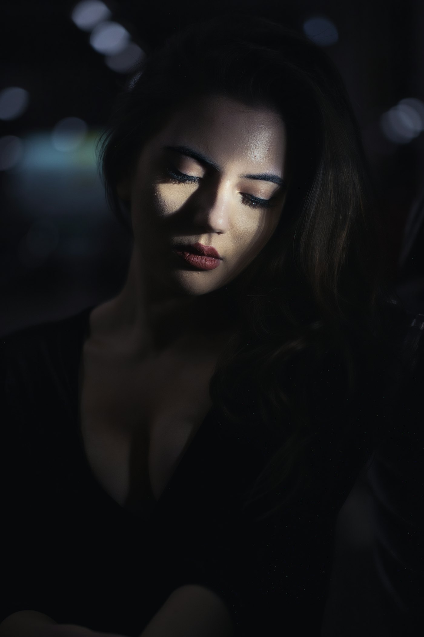 A person alone scrolling a phone in a dark room at night